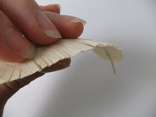 Curve the barb of the wooden feather in. Curve the barb of the wooden feather in.