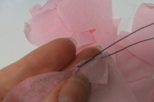 Hook the wire through the tissue paper and start to roll the petals.