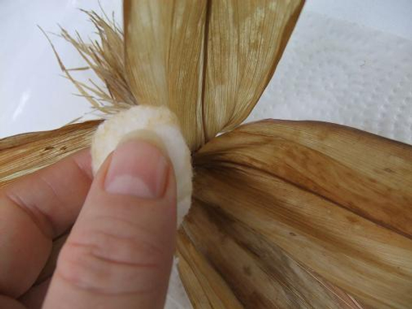 Open the leaves just below the knot and slip the cotton ball in