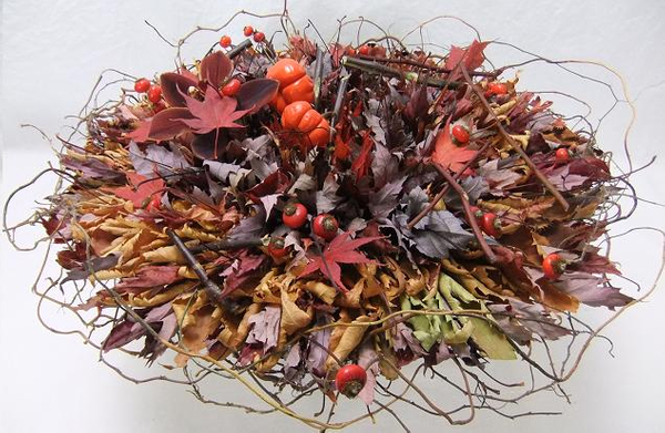 Rose hips, pumpkin tree plant, and a cymbidium orchid nestled in autumn leaves 