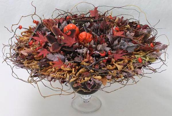 Rose hips, pumpkin tree plant, and a cymbidium orchid and willow nestled in a rosette of autumn leaves