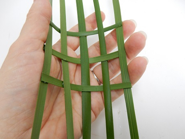 Start to bend the palm leaves by resting it in the palm of your hand