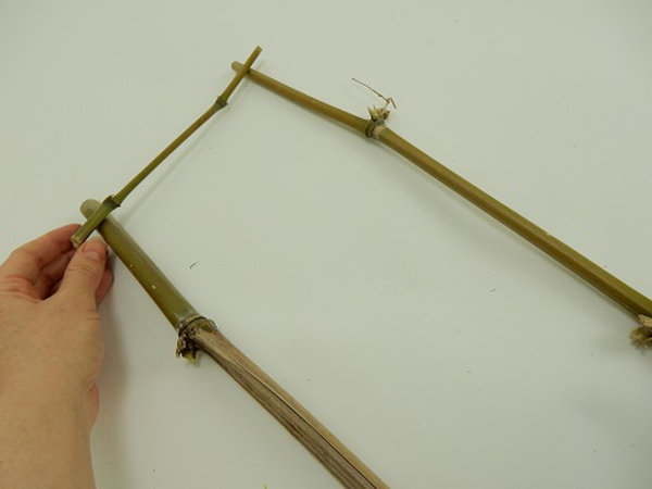 Lay two bamboo pieces on a working surface and place a thinner piece across the top