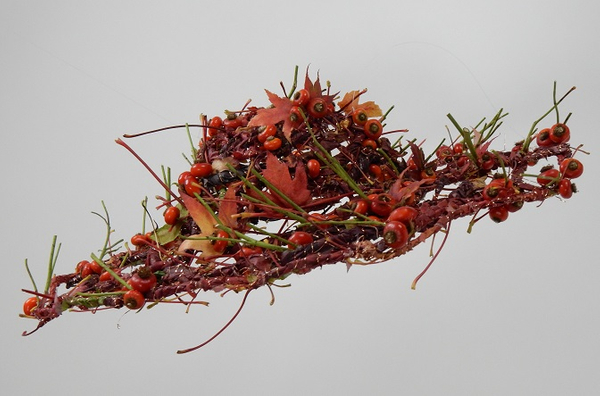 Weaving a hat with fall leaves and rose hips