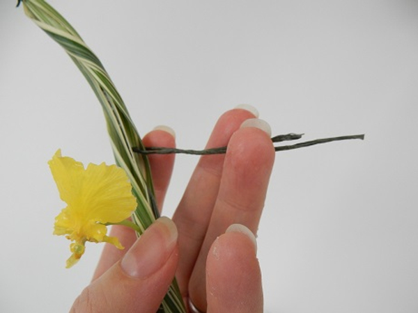 Bend a piece of wire in half and hook it through the bundle of grass