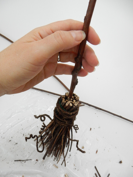 Wiggle the sharp end of the handle into the brush of the broom