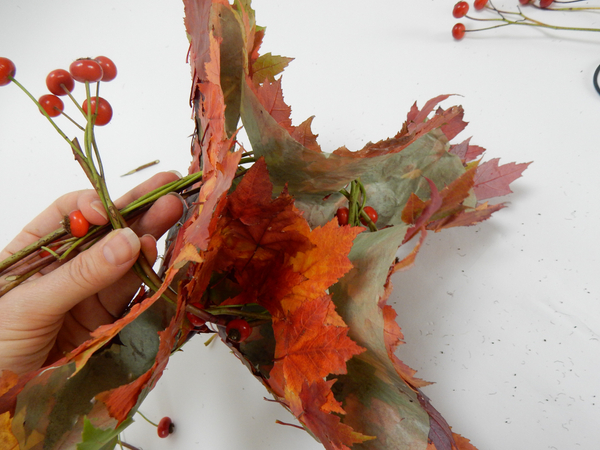 Cross the garland ends over and weave it back around and through the holes in the disk