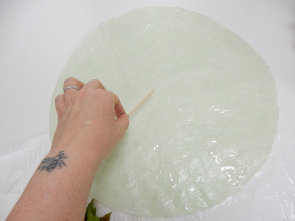Spread a thin and even layer of floral glue on a round piece of tissue paper Spread a thin and even layer of floral glue on a round piece of tissue paper