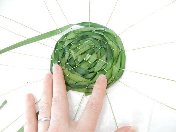 Continue weaving the garland grass to create the bowl of the hat Continue weaving the garland grass to create the bowl of the hat