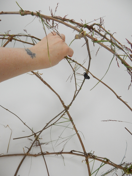 Continue to fill in the gaps between the vines by wrapping grass around it