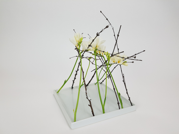 Marching frosted twig and freesia flower arrangement
