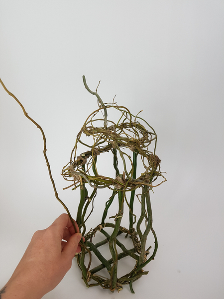 Add more pliable willow twigs all round the birdcage to secure all the twigs and to create a wild and natural look. Add more pliable willow twigs all round the birdcage to secure all the twigs and to create a wild and natural look.
