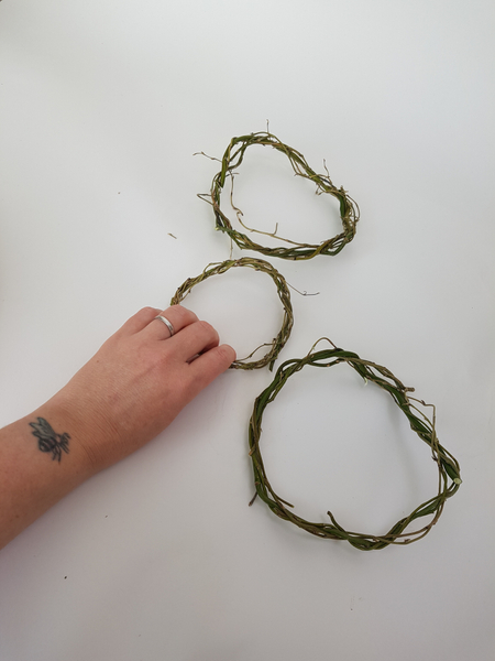 Weave three wreaths (two big and one smaller) from pliable willow twigs.