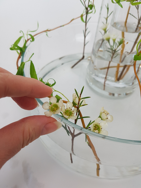 Set the flowers to rest between the willow and the glass around the edge of the container.