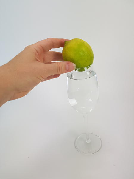 Place a lemon on the glass.  Any fruit or even vegetable or guard will work, as long as it is heavy for it's size and sits firm.