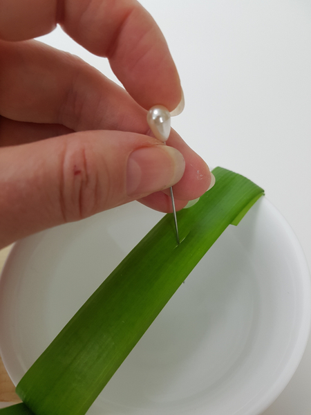 Make a tiny slit in the blade of grass with a pin.
