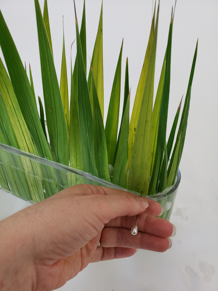 Start to rip the foliage right above the lip of the container with a corsage pin