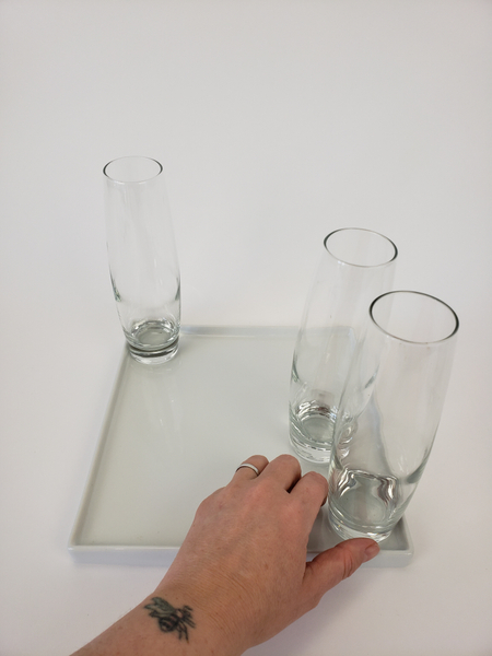 Place three bud vases in a display tray