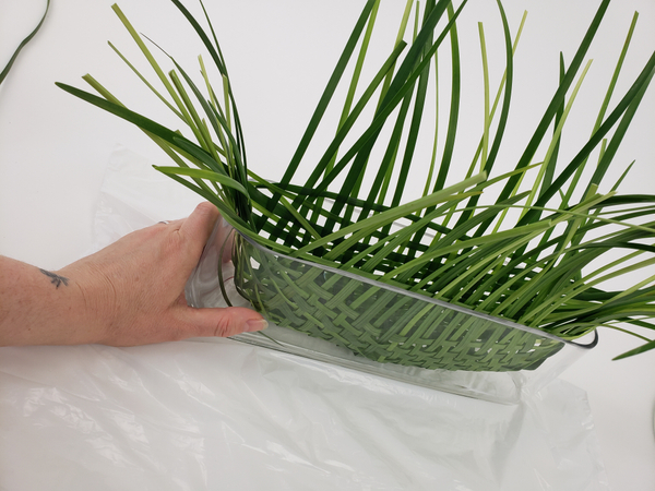 Gently curve the grass around the shape of the container to form the basket