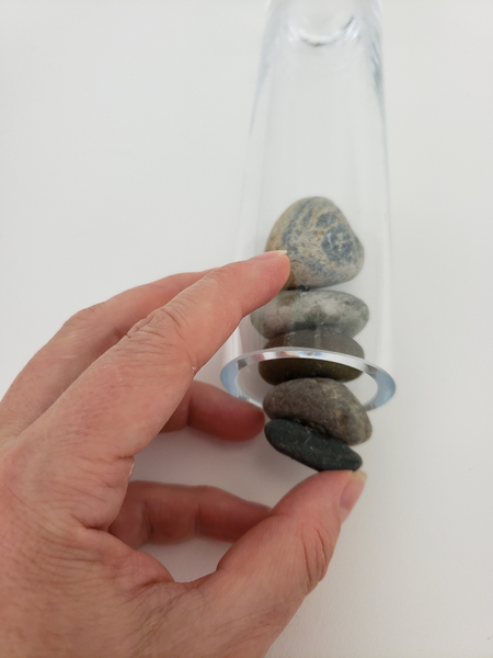 Keep the vase on its side and push each pebble in with the next.
