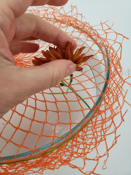 Slip the flower stems through so that the flowers rest on the net