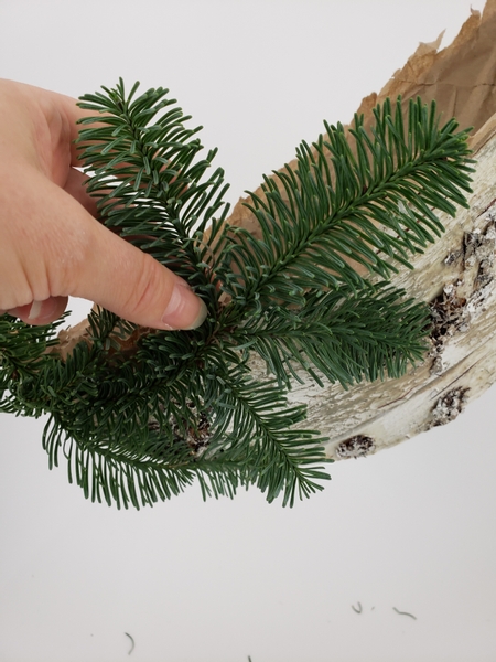 Curve some of the side branches over to the front and back of the bark covered half of the wreath