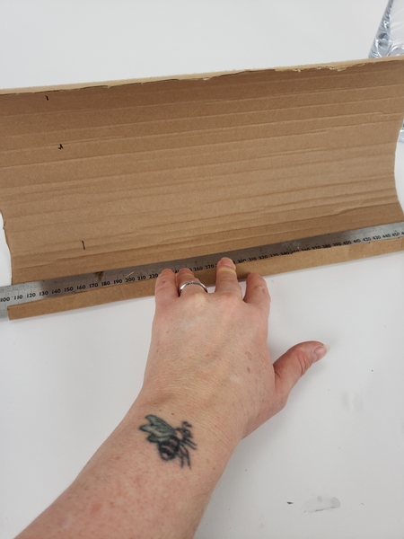 Use a steel ruler to fold an edge on the one side of the cardboard