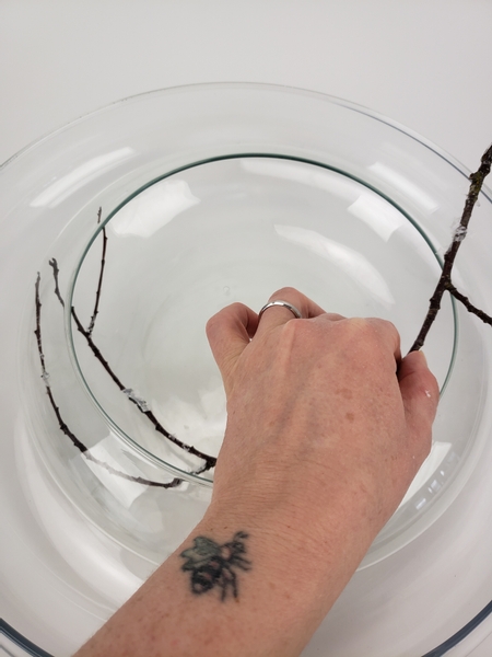 Curve the twig into the smaller vase