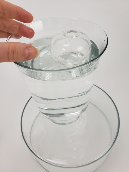 Add water to the smaller vase so that it sinks in the water to become stable