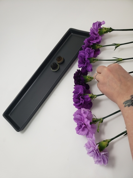 Place the carnations on a flat working surface to measure and cut the stems Place the carnations on a flat working surface to measure and cut the stems