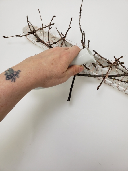 Fill the container with water between the twig and wire