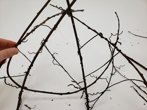 Cross a few curved twigs using the wire vines to secure them to the basket base