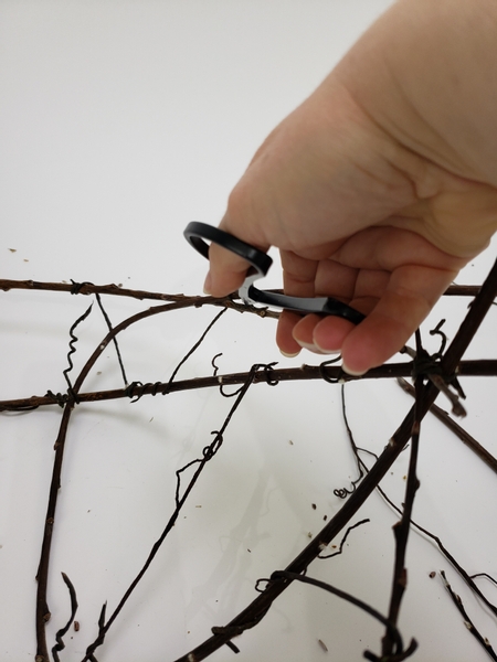 Cut the twigs that extends too far shorter so that it remains in the framework of the basic shape of the basket you crafted