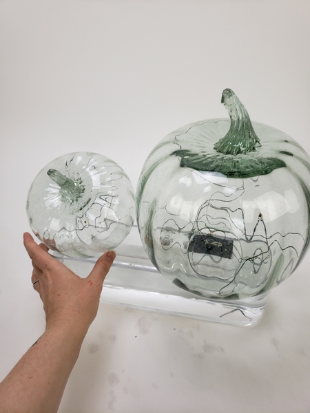 Fill the display container with water and place the heavy pumpkins on top