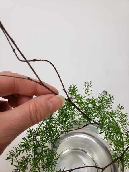 Glue a twig to the outside of the vase to peek out from the fern wreath