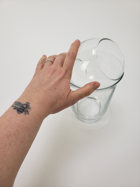 Place a fishbowl vase into a container so that it rests at an angle