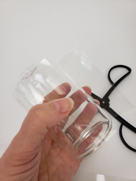 Measure and cut a section of cellophane to fit around a glass container