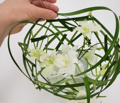 Dendrobium orchid and grass snippet cone around a glass container