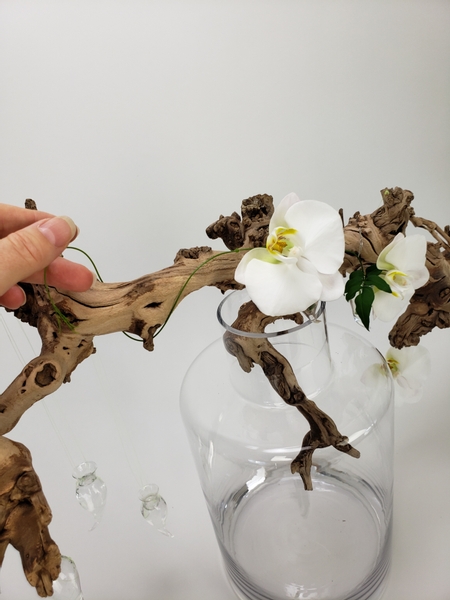Add a few jasmine vines into the vases to drape over the driftwood branch Add a few jasmine vines into the vases to drape over the driftwood branch