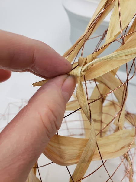 Knot the foliage to the wire at both ends so that the hat can be reshaped once done