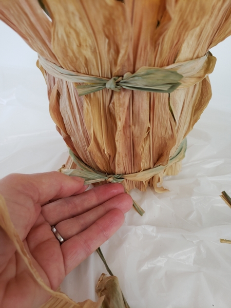 Wrap a long section of corn leaf around the vase to conceal the elastic band