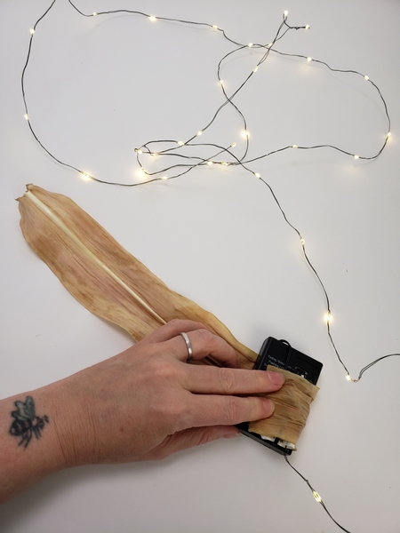 Wrap the battery pack of fairy lights with a corn leaf