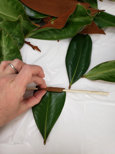 Place a skewer on the tip of the leaf and start to roll it