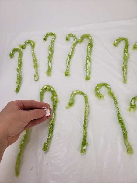 Use wood glue to dust the wool candy canes with artificial snow