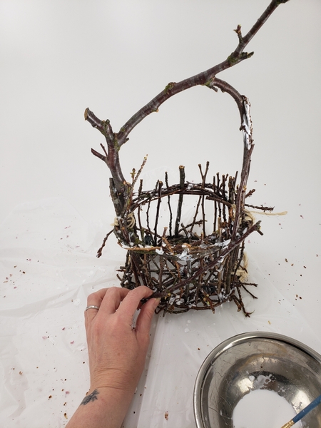 Add a few twigs into the basket to start the design and break up the formal pattern created by the wreath and twigs