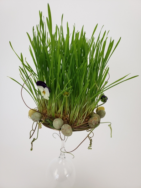 Pansies and Easter eggs in a wheatgrass nest patch for a Spring display