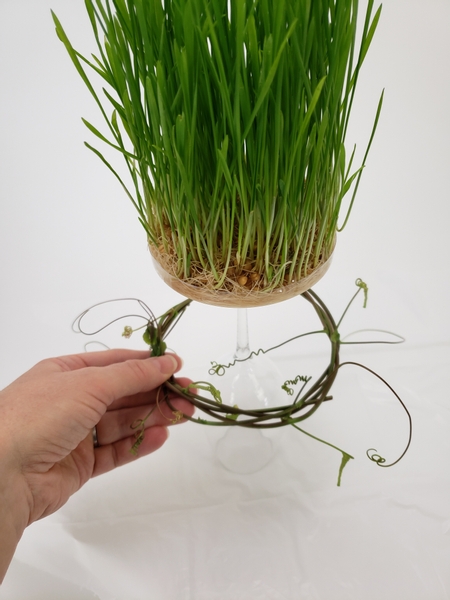 Slip the wreath from the grass side up onto the plastic rim of the seed container