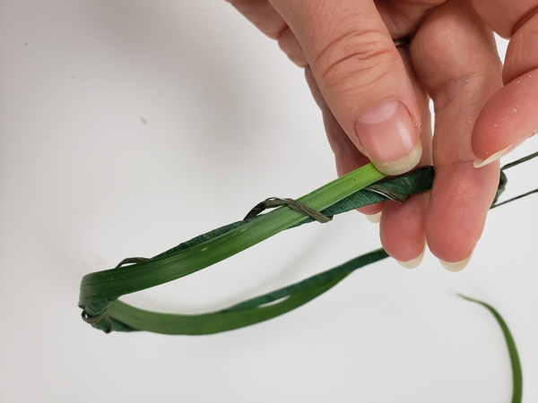 Slip an end of a blade of grass through the wire twirl and extend the grass around the egg shape