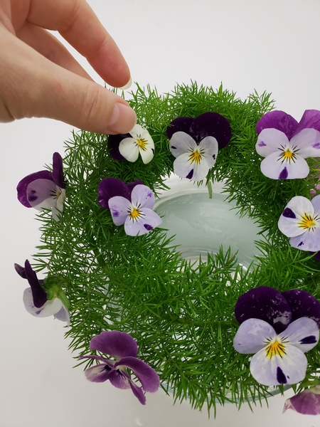 Place the violas to rest in the wreath with their stems in the water below