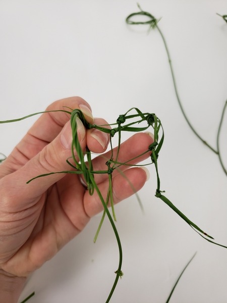 Split the pair of grass open at a knot and tie it over the wreath part of the handle